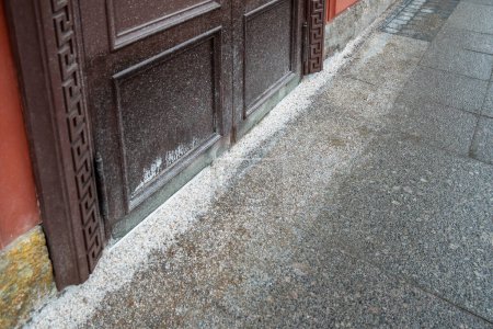 Photo for Pavement near building entrance covered with white thick layer of anti-slip thaw salt. Chemical reagent used in winter for deicing, surface frost removal in city streets, risk of falling elimination - Royalty Free Image