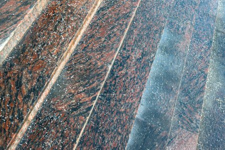 Deicing chemicals on stairs in winter. Salt grains on icy stone granite steps in cold season, close up above view. Slippery surface sprinkled with technical salt. Prevent slipping concept