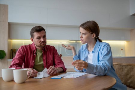 Sad thoughtful husband and bewildered wife analysing bills, receipts, money spendings, having financial difficulties, problems. Unhappy man with small income cant pay for debts, credits, utilities