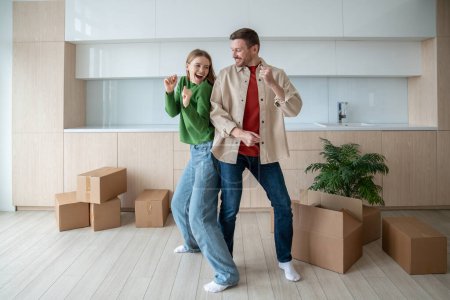 Photo for Dancing of joy and happiness, overjoy married couple have fun in spacious apartment with packed cardboard boxes. Pleased homeowners celebrating moving into own new purchased flat. Dream family home. - Royalty Free Image