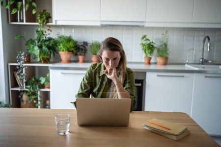 Thoughtful serious woman freelancer working from home look at screen of laptop. Busy accountant counting annual figures of financial. Frustrated female feel upset with obtained job results on computer