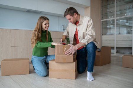 Photo for Joyful boyfriend and girlfriend excitedly preparing to move new place. Couple carefully packs things into cardboard boxes, trying not forget anything. Man and woman looking forward to new home moving. - Royalty Free Image