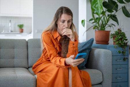 Photo for Worried woman holding cellphone, anxiously gazing at screen, awaiting call or message. Upset female read news look with tension of uncertainty on smartphone with bad thoughts in head, loss connection - Royalty Free Image