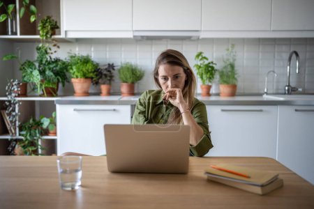 Thoughtful serious woman freelancer working from home look at screen of laptop. Busy remote accountant examines financials. Frustrated female feel upset with obtained job results. Job search online. 