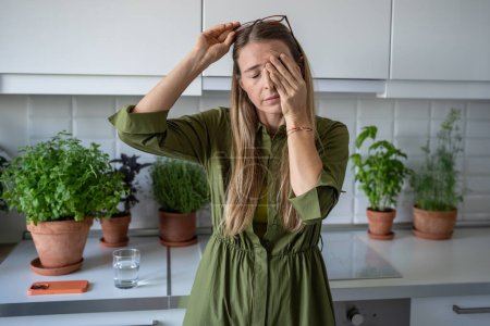 Photo for Sleepy woman suffering from chronic fatigue rubbing eyes on kitchen at home. Tired middle aged female feeling bad from lack of rest, headache, lack of energy after party, sleepless night. - Royalty Free Image