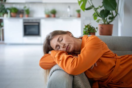 Woman put head on armrest resting on comfy sofa after working day, napping, closed eyes. Portrait relaxed female spending lazy time on couch in living room. Leisure, repose concept