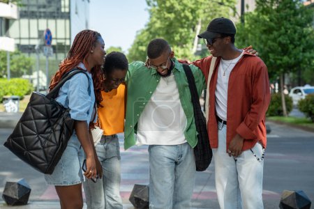 Téléchargez les photos : Joyeux heureux afro-américain quatre amis filles et les gars riant urbain marchant ensemble. Joyeux groupe heureux d'étudiants noirs s'amuser en plein air, bavarder, partager des histoires, profiter de se promener ensemble - en image libre de droit