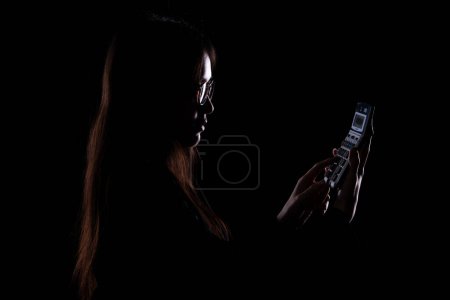 Téléchargez les photos : Silhouette de femme d'affaires tenant Calculatrice sur fond noir. Comptable à la recherche de la vérité fait du budget du bilan et où se cacher chercher concept d'argent caché - en image libre de droit
