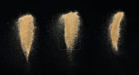 Foto de Explosión de arena voladora, explosión de onda de arena dorada. Las arenas abstractas nublan. Salpicadura de arena de color amarillo lanzando al aire. Fondo negro Obturador de alta velocidad aislado, lanzando movimiento de parada de congelación - Imagen libre de derechos