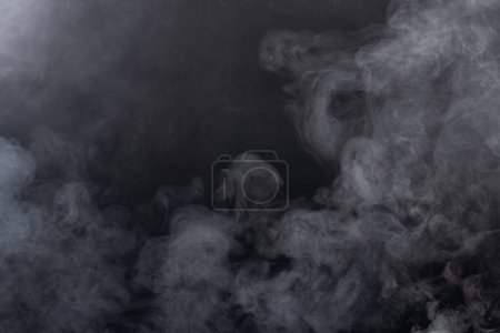 Foto de Densa esponja esponjosa de humo blanco y niebla sobre fondo negro, nubes de humo abstracto, movimiento borroso fuera de foco. Fumar golpes de la máquina de hielo seco volar revoloteando en el aire, textura efecto - Imagen libre de derechos