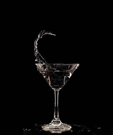 Photo for Cocktail Glass with splashing water alcohol, Crystal Cocktail drink splatter splash in air and bubble from glass. Liquor Part freeze shot high speed over black background isolated - Royalty Free Image