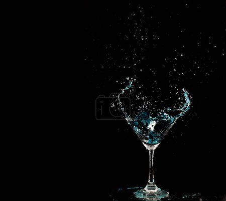 Photo for Blue Cocktail Glass with splashing water alcohol, Crystal Cocktail drink splatter splash in air and bubble from glass. Liquor Part freeze shot high speed over black background isolated - Royalty Free Image