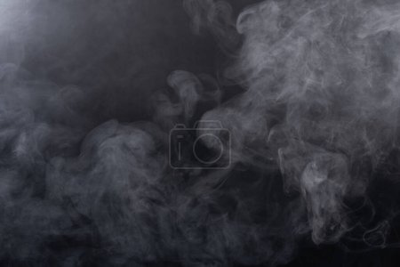 Photo for Dense Fluffy Puffs of White Smoke and Fog on black Background, Abstract Smoke Clouds, Movement Blurred out of focus. Smoking blows from machine dry ice fly fluttering in Air, effect texture - Royalty Free Image