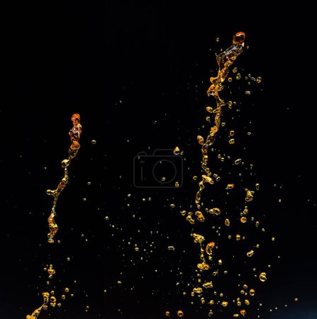 Photo for Orange, lemon juice or oil lubricant splash, liquid gold yellow drink drops. Fruit beverage water elements in line form . Fresh splashing and flowing jets, black background isolated freeze motion - Royalty Free Image