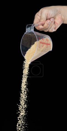 Photo for Brown Sugar fall, brown grain sugar pouring down abstract cloud fly from measuring cup. Beautiful complete seed sugarcane, food object design. Selective focus freeze shot Black background isolated - Royalty Free Image