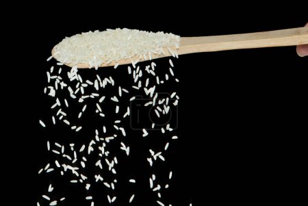 Japanischer Reis fällt, weiße Kornrispen ergießen sich abstrakte Wolkenfliege vom Löffel herab. Schöne komplette Samen Reis in der Luft, Lebensmittel-Objekt-Design. Selektiver Fokus Freeze Shot Schwarzer Hintergrund isoliert