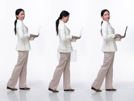 Photo for Full length 20s Asian Woman wear formal business blazer suit  dress pant shoes. Black long straight hair female hold laptop work confident, walk forward turn left right, white background isolated - Royalty Free Image