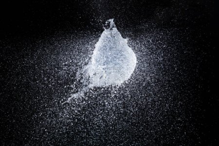 Foto de Water balloon explosion splashing in form shape, is power refreshing freshness concept. Waters Balloon explode and droplet spill all around with freeze high speed shot in black background studio - Imagen libre de derechos