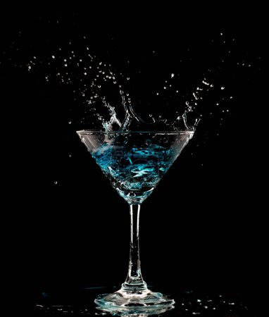 Téléchargez les photos : Verre à cocktail bleu avec éclaboussures d'alcool d'eau, éclaboussures de boisson Crystal Cocktail dans l'air et bulle de verre. Liquor Part gel tourné à grande vitesse sur fond noir isolé - en image libre de droit