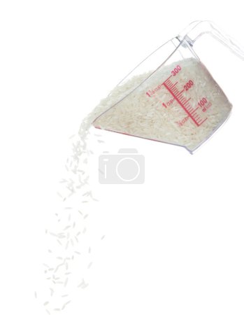 Foto de Otoño de arroz japonés, arroz de grano blanco vertiendo una nube abstracta que vuela de la taza de medición. Hermoso arroz de semilla completa en el aire, diseño de objetos alimenticios. Congelación de enfoque selectivo plano fondo blanco aislado - Imagen libre de derechos