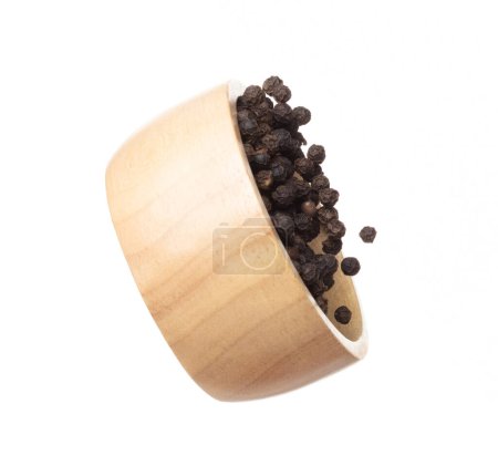 Foto de Black Pepper seeds fly throw up in wooden bowl, Black Pepper float explode, abstract cloud fly. Black Peppercorn splash throwing in Air. White background Isolated high speed shutter, freeze motion - Imagen libre de derechos