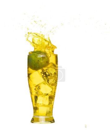 Téléchargez les photos : Versez du jus de citron vert dans du verre à glaçons, le jus de citron vert tombe dans de l'eau liquide jaune. citron vert dans le jus jeter éclaboussure dans l'air. Fond blanc Obturateur haute vitesse isolé, action de gel - en image libre de droit