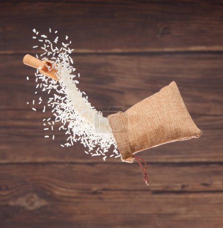 Foto de Japanese Rice in sack bag flying explosion, white grain rices fall abstract fly. Beautiful complete seed rice bag splash in air, food object design. Wood kitchen background, high speed freeze motion - Imagen libre de derechos