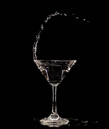 Téléchargez les photos : Cocktail verre avec éclaboussures d'alcool d'eau, Cristal Cocktail boisson éclaboussure éclaboussure dans l'air et bulle de verre. Liquor Part gel tourné à grande vitesse sur fond noir isolé - en image libre de droit