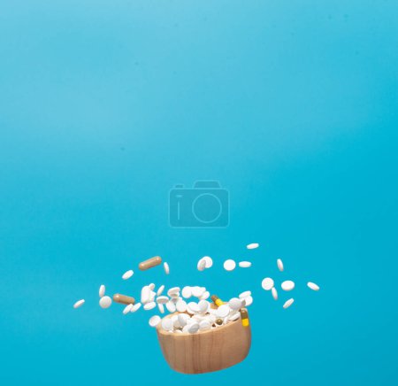 Photo for Daily pill drug medicine falling down float in bowl. Many kind of drugs pills medicines to help patient fly to senior. Mixed combination Drug pill medicine Medical over blue background isolated - Royalty Free Image