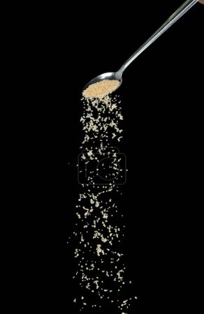 Photo for Brown Sugar fall, brown grain sugar pouring down abstract cloud fly from silver spoon. Beautiful complete seed sugarcane, food object design. Selective focus freeze shot Black background isolated - Royalty Free Image