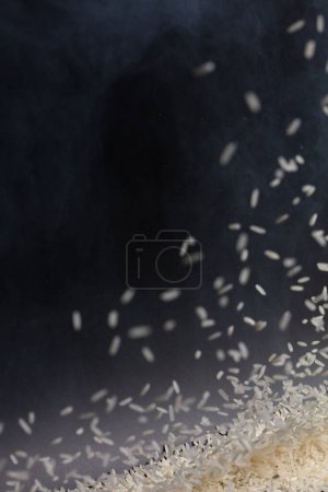 Foto de Explosión voladora de arroz japonés, los arroces de grano blanco explotan la nube abstracta vuela. Hermosa semilla completa salpicadura de arroz en el aire, diseño de objetos alimenticios. Fondo negro de alta velocidad obturador congelar movimiento de parada - Imagen libre de derechos