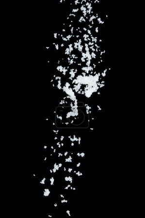 Foto de Explosión volante de sal, sales de grano blanco cristal explotan mosca nube abstracta. Hermosa semilla completa salpicadura de sal en el aire, diseño de objetos alimenticios. Congelación de enfoque selectivo tiro fondo negro aislado - Imagen libre de derechos