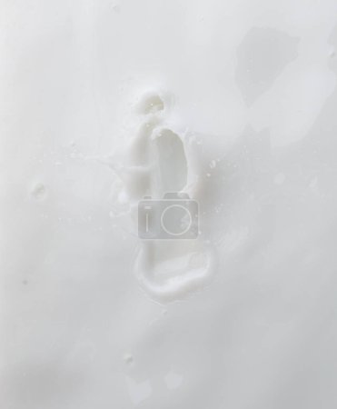 Foto de Recipiente cosmético blanco loción gotita mosca salpicadura. Loción de leche vierta flotador a la botella cosmética. Derrame de explosión de loción hidratante. Fondo blanco aislado obturador de alta velocidad congelar vista superior - Imagen libre de derechos