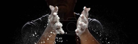 Photo for Chef prepare white flour dust for cooking bakery food. Elderly man Chef clap hand, white flour dust explode fly in air. Flour stop motion in air with freeze high speed shutter, black background - Royalty Free Image