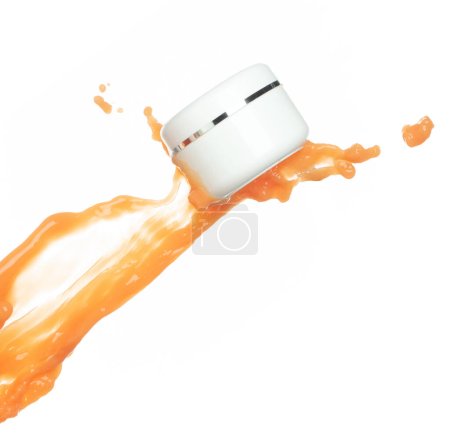 Foto de Crema de loción hidratante de jugo de naranja que se vierte en un recipiente de botella cosmética. Pintura naranja loción belleza revoloteando explosión en el aire, salpicadura derrame como gota de explosión. Fondo blanco aislado - Imagen libre de derechos