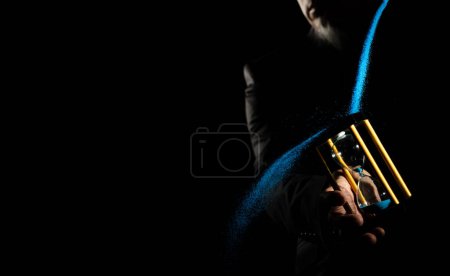 Photo for Hourglass is money sand of time, business man pouring blue sand into hourglass to add more time in his life. Deadline extended time management hope concept to gold hour glass. Black background old man - Royalty Free Image