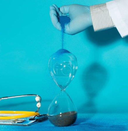 Photo for Medical technology, we can now extend more time to people's life, The goal of medicine is to prolong more time to people's lives and improve their quality of life. Doctor pouring sand to hourglass - Royalty Free Image