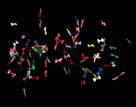 Photo for Bows flying in air. Many small ribbon in red, blue, pink, yellow throw explosion. Small Bow floating abstract black background isolated, high speed shutter freeze action - Royalty Free Image