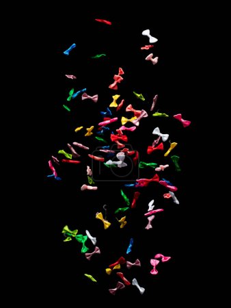 Foto de Arcos volando en el aire. Muchos cinta pequeña en rojo, azul, rosa, explosión de tiro amarillo. Pequeño arco flotante abstracto negro fondo aislado, alta velocidad obturador congelar acción - Imagen libre de derechos