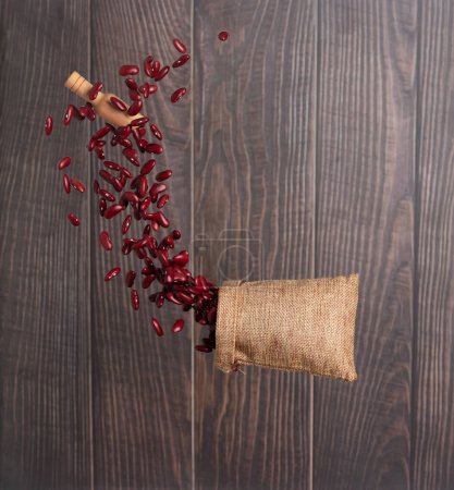 Photo for Red Bean flying explosion in sack bag, red grain beans explode abstract cloud fly. Beautiful complete seed pea bean bag splash in air, food object design. Wooden background isolated freeze shot - Royalty Free Image