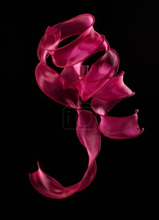 Photo for Red rose ribbon long straight fly in air with curve roll shiny. Red yellow ribbon for present gift birthday party to wrap around decorate, curl curve long straight. Black background isolated - Royalty Free Image