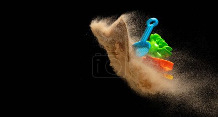 Téléchargez les photos : Jouet en plastique de plage de sable pour enfant à jouer le long de la mer océan plage est rouge bleu jaune vert. Creuser mouche jouet de moulage avec du sable dans l'air, Kid profiter de jouer jouet coloré. Fond noir isolé - en image libre de droit