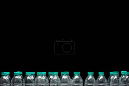 Téléchargez les photos : Support de bouteille en plastique organiser, mur de bouteille en plastique pour animaux de compagnie avec couvercle vert. Bouteilles d'eau en plastique pleine longueur utilisées alignent. fond noir isolé papier peint - en image libre de droit