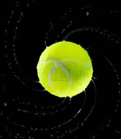 Téléchargez les photos : Balle de tennis a frappé l'eau et éclabousser dans l'air. Boule de tennis verte voler sous la pluie et éclabousser spin éclaboussure dans l'eau gouttelette. fond noir isolé gel action - en image libre de droit