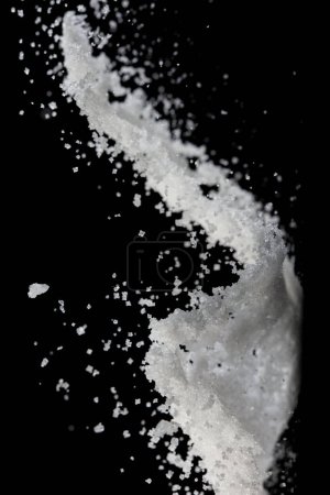 Téléchargez les photos : Poudre de sel verser tomber dans un bol, blanc Cristal de sel cuire mouche nuage abstraite. Éclaboussure de sel moulu dans l'air, conception d'éléments alimentaires. Fond noir isolé foyer sélectif flou - en image libre de droit