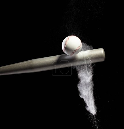 Photo for Baseball player hit ball with silver bat and sand soil explode in air. Baseball players in dynamic action hit ball smoke tail. Black background isolated freeze action - Royalty Free Image