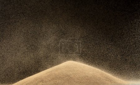 Foto de La arena cae en la colina como una lluvia y salpica en el aire. Duna de arena colina sobre tormenta de viento y polvo de explosión salpicadura sobre la montaña. Lluvia de sol cae sobre arena soplo de viento colina. Fondo negro aislado - Imagen libre de derechos