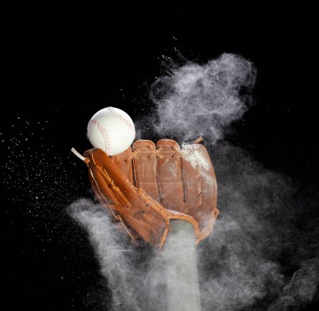 Foto de Guante de cuero guante recibir bola de béisbol golpeado y polvo suelo explota en el aire. Bola de béisbol lanzar y golpear al centro del guante del guante. Fondo negro Serie aislada dos de imágenes - Imagen libre de derechos