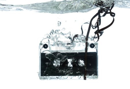 Photo for Cassette retro vintage Tape fall into clear water with air bubble. Black retro vintage cassette magnetic tape drop to wash old time. White background isolated freeze element - Royalty Free Image
