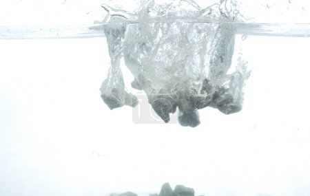 Téléchargez les photos : Construction Gravier de roche jeter tomber dans l'eau claire avec bulle d'air. Pierre grise cailloux goutte de roche pour nettoyer l'eau de ciment. Blanc fond isolé élément de congélation - en image libre de droit